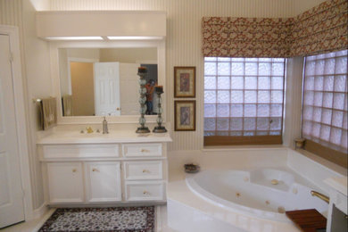 ヒューストンにある中くらいなトラディショナルスタイルのおしゃれなマスターバスルーム (落し込みパネル扉のキャビネット、白いキャビネット、コーナー型浴槽、ベージュの壁、磁器タイルの床、一体型シンク、人工大理石カウンター、白い床、白い洗面カウンター) の写真