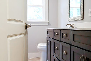 Idée de décoration pour une salle de bain principale tradition en bois foncé de taille moyenne avec un placard à porte shaker, un mur gris, un sol en travertin, un plan de toilette en quartz modifié et un sol beige.