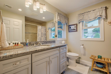 Bild på ett mellanstort vintage en-suite badrum, med luckor med infälld panel, grå skåp, en dusch i en alkov, en toalettstol med hel cisternkåpa, vita väggar, ett undermonterad handfat, grått golv och dusch med duschdraperi