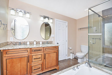 オタワにある高級な中くらいなコンテンポラリースタイルのおしゃれなマスターバスルーム (アンダーカウンター洗面器、レイズドパネル扉のキャビネット、淡色木目調キャビネット、御影石の洗面台、ドロップイン型浴槽、シャワー付き浴槽	、分離型トイレ、茶色いタイル、セラミックタイル、ベージュの壁、セラミックタイルの床) の写真