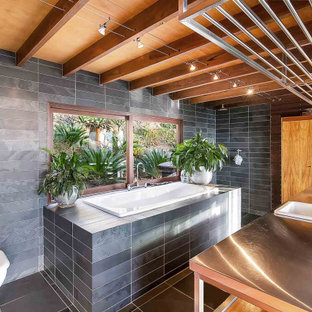 Inspiration for a tropical master bathroom in Sydney with a drop-in tub, an open shower, gray tile, grey walls, a drop-in sink, stainless steel benchtops, grey floor and an open shower.