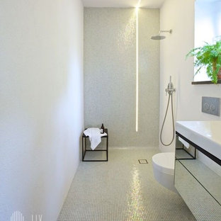 Foto di una stanza da bagno industriale con pareti bianche, pavimento con piastrelle a mosaico, ante di vetro, ante in legno scuro, doccia ad angolo, WC sospeso, piastrelle bianche, piastrelle di vetro, lavabo integrato e top in vetro