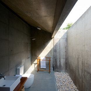 Idee per una stanza da bagno moderna di medie dimensioni con top in legno, WC monopezzo, piastrelle grigie, piastrelle di cemento, lavabo a bacinella, doccia a filo pavimento e top marrone