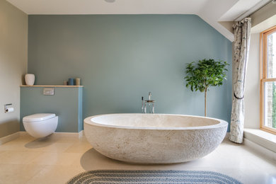 Freestanding bathtub - transitional master beige floor freestanding bathtub idea in Belfast with a wall-mount toilet and blue walls