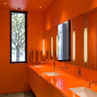 Inredning av ett modernt orange oranget badrum, med ett undermonterad handfat, släta luckor, orange skåp och orange väggar