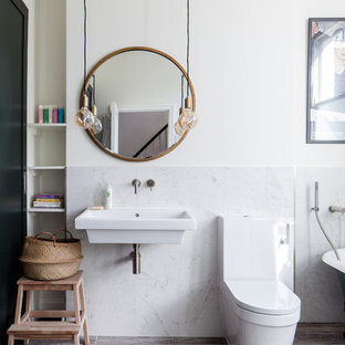 Classic shower room bathroom in London with a claw-foot bath, a shower/bath combination, a one-piece toilet, white tiles, marble tiles, white walls, a wall-mounted sink and brown floors.