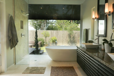 Modelo de cuarto de baño tradicional renovado con lavabo sobreencimera, puertas de armario de madera en tonos medios, encimera de granito, bañera exenta, ducha abierta y baldosas y/o azulejos beige