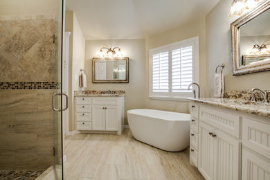 Example of a classic multicolored tile and porcelain tile travertine floor freestanding bathtub design in Dallas with beaded inset cabinets, white cabinets, granite countertops and beige walls