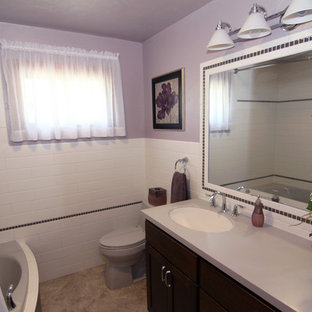 Kleines Klassisches Badezimmer En Suite mit flächenbündigen Schrankfronten, dunklen Holzschränken, Eckbadewanne, Duschbadewanne, Wandtoilette mit Spülkasten, weißen Fliesen, Metrofliesen, lila Wandfarbe, Vinylboden, integriertem Waschbecken und Mineralwerkstoff-Waschtisch in Milwaukee