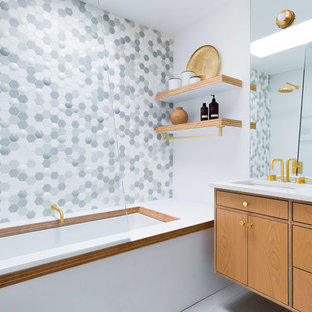 Photo of a mid-sized midcentury kids bathroom in Portland with flat-panel cabinets, light wood cabinets, an undermount tub, a shower/bathtub combo, gray tile, multi-coloured tile, white tile, mosaic tile, white walls, an undermount sink, grey floor, white benchtops, solid surface benchtops and an open shower.