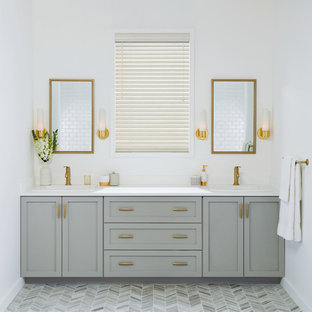 Diseño de cuarto de baño principal, tradicional renovado, de tamaño medio, con armarios estilo shaker, puertas de armario grises, paredes blancas, suelo gris, suelo de baldosas de porcelana, lavabo encastrado, encimera de cuarzo compacto y encimeras blancas