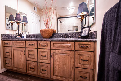 Mid-sized southwest kids' beige tile and porcelain tile porcelain tile and brown floor bathroom photo in Other with raised-panel cabinets, medium tone wood cabinets, a two-piece toilet, beige walls, an undermount sink, granite countertops and black countertops