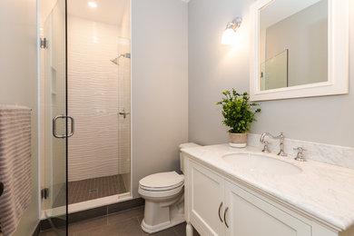 Small contemporary shower room bathroom in Boston with freestanding cabinets, white cabinets, an alcove shower, a one-piece toilet, white tiles, ceramic tiles, grey walls, porcelain flooring, a submerged sink, marble worktops, grey floors, a hinged door and white worktops.