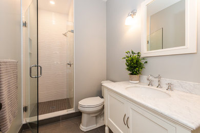 Alcove shower - small contemporary 3/4 white tile and ceramic tile porcelain tile and gray floor alcove shower idea in Boston with furniture-like cabinets, white cabinets, a one-piece toilet, gray walls, an undermount sink, marble countertops, a hinged shower door and white countertops