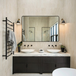Design ideas for a contemporary master bathroom in Adelaide with furniture-like cabinets, dark wood cabinets, a freestanding tub, beige tile, beige walls, a vessel sink, marble benchtops, beige floor and white benchtops.