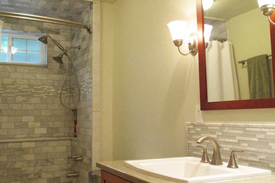 シアトルにあるお手頃価格の中くらいなトランジショナルスタイルのおしゃれなバスルーム (浴槽なし) (オーバーカウンターシンク、シェーカースタイル扉のキャビネット、中間色木目調キャビネット、人工大理石カウンター、アルコーブ型浴槽、分離型トイレ、白いタイル、石タイル、緑の壁、磁器タイルの床、シャワー付き浴槽	) の写真