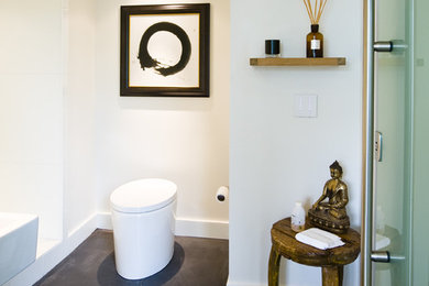 マイアミにあるラグジュアリーなコンテンポラリースタイルのおしゃれな浴室 (壁付け型シンク、アルコーブ型シャワー、一体型トイレ	、ベージュの壁、コンクリートの床) の写真
