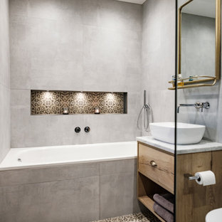 Modern inredning av ett mellanstort en-suite badrum, med skåp i mellenmörkt trä, en öppen dusch, en vägghängd toalettstol, grå kakel, ett fristående handfat, med dusch som är öppen, ett platsbyggt badkar, porslinskakel, klinkergolv i porslin och marmorbänkskiva