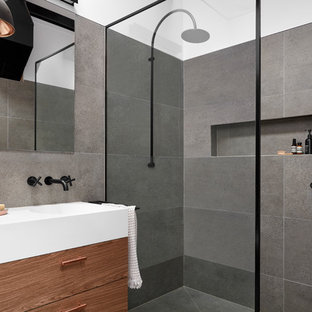Photo of a small industrial 3/4 bathroom in Melbourne with flat-panel cabinets, dark wood cabinets, gray tile, porcelain tile, porcelain floors, an integrated sink, solid surface benchtops, grey floor, an open shower, a corner shower and grey walls.