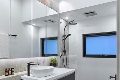 Exempel på ett litet modernt badrum, med släta luckor, svarta skåp, en vägghängd toalettstol, grå kakel, porslinskakel, klinkergolv i porslin, ett fristående handfat, bänkskiva i akrylsten, en dusch i en alkov och med dusch som är öppen