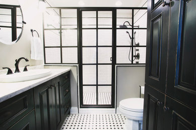 Wet room - mid-sized industrial master marble tile laminate floor and multicolored floor wet room idea in Other with recessed-panel cabinets, black cabinets, a two-piece toilet, gray walls, a drop-in sink and a hinged shower door