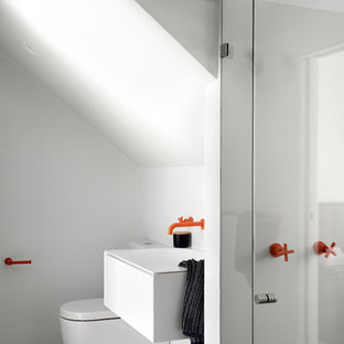 This is an example of a contemporary master bathroom in Sydney with flat-panel cabinets, white cabinets, a corner shower, white tile, white walls, a console sink, grey floor and a hinged shower door.