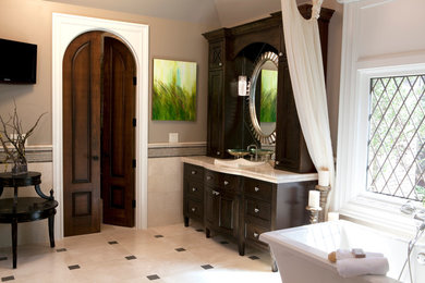アトランタにある高級なトラディショナルスタイルのおしゃれなマスターバスルーム (ベッセル式洗面器、濃色木目調キャビネット、置き型浴槽、ベージュのタイル、グレーの壁、セラミックタイルの床) の写真