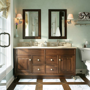Inspiration for a mid-sized traditional master bathroom in New York with dark wood cabinets, a two-piece toilet, white tile, stone tile, green walls, marble floors, an undermount sink, limestone benchtops, raised-panel cabinets, an alcove shower, white floor and a hinged shower door.