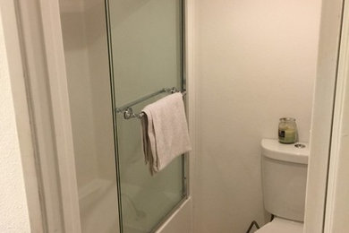 Modelo de cuarto de baño clásico pequeño con bañera empotrada, combinación de ducha y bañera, sanitario de dos piezas, paredes blancas, suelo de baldosas de porcelana y aseo y ducha