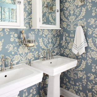 Photo of a mid-sized shabby-chic style master bathroom in New York with a pedestal sink, blue walls, dark hardwood floors, glass-front cabinets and white cabinets.