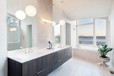 Diseño de cuarto de baño principal grande con lavabo bajoencimera, puertas de armario de madera en tonos medios, bañera empotrada, baldosas y/o azulejos beige y paredes blancas