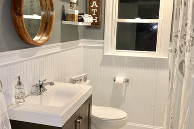 Example of a mid-sized beach style 3/4 marble floor and gray floor bathroom design in New York with recessed-panel cabinets, dark wood cabinets, a two-piece toilet, gray walls, an integrated sink, quartz countertops and white countertops