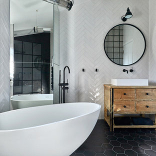 Inspiration for a medium sized contemporary ensuite bathroom in London with light wood cabinets, a freestanding bath, white tiles, ceramic tiles, white walls, a vessel sink, wooden worktops, black floors, freestanding cabinets, brown worktops, a walk-in shower, a wall mounted toilet, porcelain flooring and an open shower.
