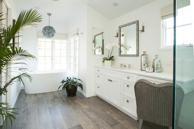 ロサンゼルスにあるトラディショナルスタイルのおしゃれな浴室 (シェーカースタイル扉のキャビネット、白いキャビネット、置き型浴槽、白い壁、濃色無垢フローリング、アンダーカウンター洗面器、茶色い床) の写真