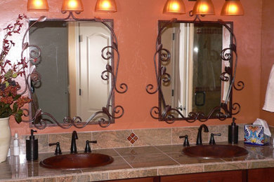 フェニックスにある中くらいなラスティックスタイルのおしゃれなマスターバスルーム (オーバーカウンターシンク、中間色木目調キャビネット、オレンジの壁、フラットパネル扉のキャビネット、御影石の洗面台) の写真
