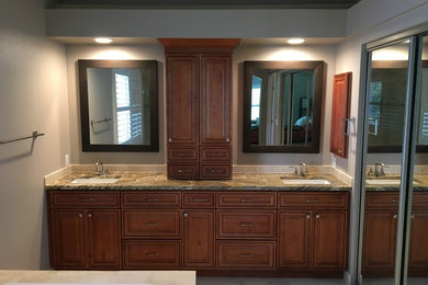 Bathroom - mid-sized traditional beige tile and marble tile marble floor and beige floor bathroom idea in Orlando with raised-panel cabinets, medium tone wood cabinets, a two-piece toilet, brown walls, an undermount sink, granite countertops and a hinged shower door