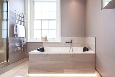 Design ideas for a medium sized contemporary family bathroom in London with a built-in bath, a built-in shower, a wall mounted toilet, beige tiles, porcelain tiles, beige walls, porcelain flooring, a pedestal sink, beige floors and a hinged door.