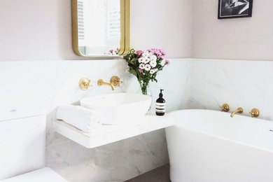 Imagen de cuarto de baño actual de tamaño medio con bañera exenta, sanitario de dos piezas, baldosas y/o azulejos grises, baldosas y/o azulejos blancos, baldosas y/o azulejos de mármol, paredes rosas, lavabo sobreencimera y suelo gris