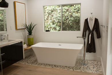 Inspiration for a mid-sized master light wood floor and brown floor bathroom remodel in Seattle with glass-front cabinets, black cabinets, a one-piece toilet, white walls, a drop-in sink, marble countertops and a hinged shower door