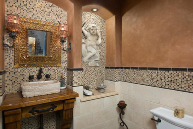 Small tuscan stone tile bathroom photo in San Diego with a vessel sink and wood countertops