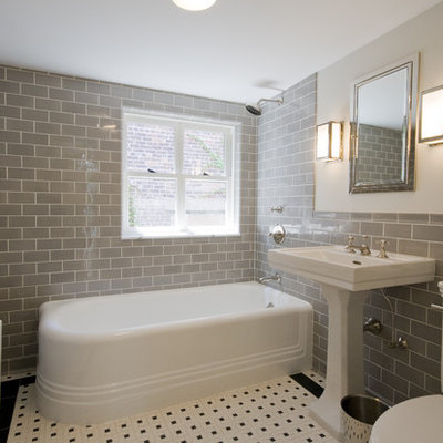 Corner bathtub - traditional subway tile and gray tile corner bathtub idea in New York with a pedestal sink