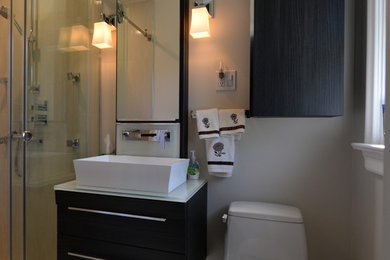 Example of a small trendy master gray tile and porcelain tile porcelain tile alcove shower design in Toronto with flat-panel cabinets, dark wood cabinets, a one-piece toilet, beige walls, a vessel sink and glass countertops