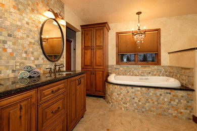 Example of a mid-sized mountain style master multicolored tile and stone tile porcelain tile bathroom design in Minneapolis with an undermount sink, raised-panel cabinets, medium tone wood cabinets, granite countertops, a one-piece toilet and beige walls