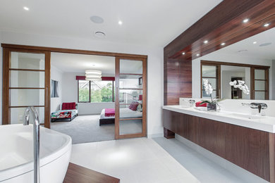 Modernes Badezimmer mit hellbraunen Holzschränken, freistehender Badewanne, Wandtoilette mit Spülkasten, beigen Fliesen und Keramikboden in Melbourne