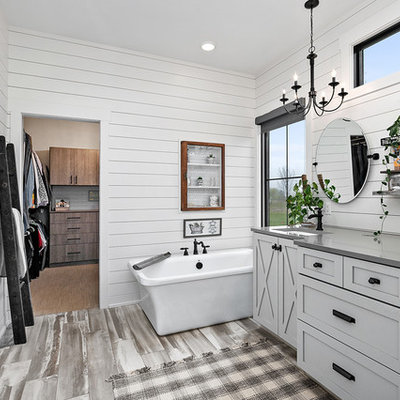 Freestanding bathtub - country master gray floor freestanding bathtub idea in Grand Rapids with shaker cabinets, gray cabinets, white walls, an undermount sink, quartz countertops and gray countertops