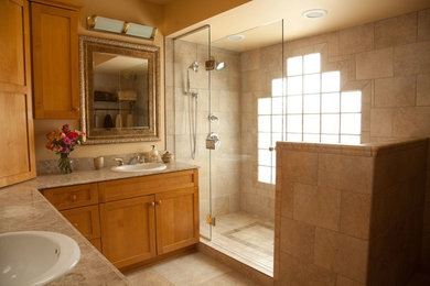 Example of a large classic master beige tile and ceramic tile ceramic tile and beige floor alcove shower design in Milwaukee with shaker cabinets, medium tone wood cabinets, yellow walls, a drop-in sink, granite countertops and a hinged shower door