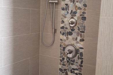 Cette image montre une douche en alcôve design avec un carrelage marron, des carreaux de céramique et un sol en galet.