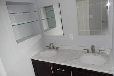 Example of a mid-sized 3/4 gray tile and ceramic tile ceramic tile alcove shower design in New York with an undermount sink, flat-panel cabinets, dark wood cabinets, marble countertops, a two-piece toilet and blue walls