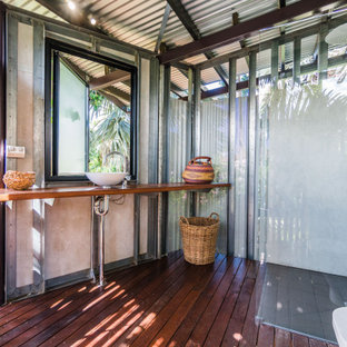 Photo of a tropical bathroom in Darwin with a corner shower, gray tile, dark hardwood floors, a vessel sink, wood benchtops, brown floor, an open shower, brown benchtops and a single vanity.