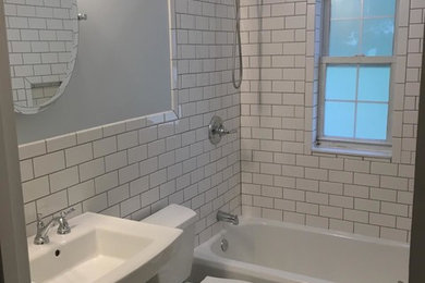 他の地域にあるお手頃価格の小さなコンテンポラリースタイルのおしゃれな浴室 (シャワー付き浴槽	、分離型トイレ、グレーのタイル、磁器タイル、白い壁、磁器タイルの床、ペデスタルシンク) の写真